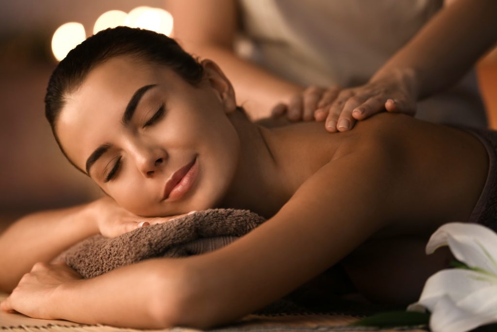 Beautiful young woman receiving massage in spa salon